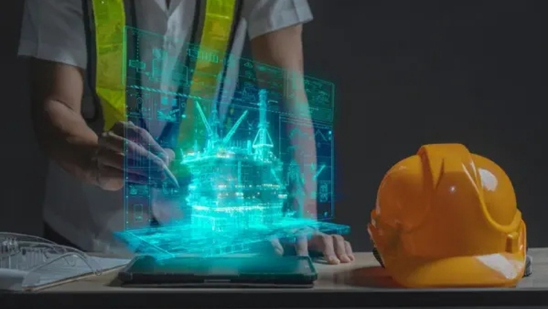 Engineer using laptop displaying digital offshore platform model, hard hat and safety vest visible