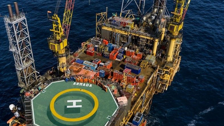 Offshore oil platform with helipad and crew standing on deck
