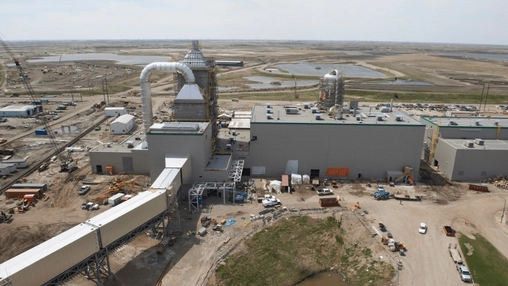 Aerial view of an industrial plant under construction with large ventilation stacks on flat open terrain